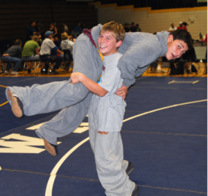 Eighth-grade Michael Macchiavello being lifted by a younger Blake Barber at wrestling practice.